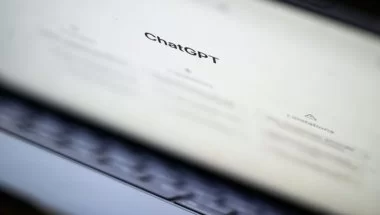A imagem mostra um notebook semiaberto, com a tela principal do ChatGPT aberta. O logo do serviço de Inteligência Artificial está em destaque, enquanto os demais elementos aparecem borrados na tela.