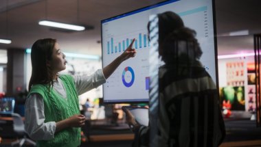 A imagem mostra duas pessoas conversando em um escritório. Elas estão analisando alguns gráficos que estão em uma tela e discutindo novas formas de trabalhar com geração de leads.
