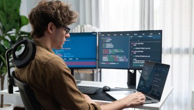 A imagem mostra um rapaz branco de óculos trabalhando em um computador. Nas telas, há diversas linhas de código de programação, indicando que ele conseguiu um emprego nessa área após criar e divulgar um portfólio front-end.