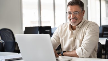 A imagem mostra um homem de meia-idade em um escritório digitando em um notebook. Ele possivelmente está analisando um slug que foi criado para a publicação de um post em seu blog.