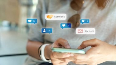 Imagem das mãos de uma mulher branca. Os dedos polegares estão prestes a clicar em um smartphone. Artes gráficas de emojis e comentários de usuários da internet aparecem ao redor do aparelho. O tema do artigo é tráfego orgânico.