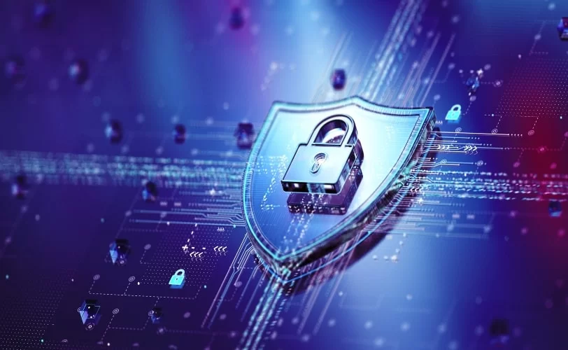 A imagem apresenta um conceito digital de cibersegurança, com um grande escudo metálico e um cadeado no centro, simbolizando proteção de dados e segurança digital. O fundo em azul e preto exibe um ambiente tecnológico com circuitos, cadeados menores e fluxos de dados, representando a proteção de informações na internet que pode ser garantida com um certificado SSL. 