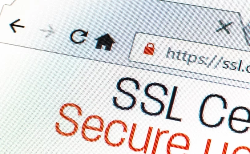 A imagem mostra um close-up de um navegador de internet com a URL iniciando em "https://", acompanhado de um ícone de cadeado vermelho, indicando um possível alerta de segurança. Para conter problemas do tipo, o ideal é usar um certificado SSL na página.