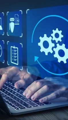 A imagem mostra uma cena conceitual de automação e tecnologia digital. Um profissional está digitando em um notebook, enquanto sobre a tela aparecem ícones digitais em azul, representando diferentes processos: engrenagens, checklist, segurança, inteligência artificial e validações. O destaque principal é o ícone de engrenagens em movimento, cercado por setas circulares, simbolizando o fluxo contínuo de automação de tarefas.