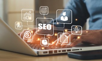 Pessoa digitando em um notebook com ícones digitais flutuantes relacionados a SEO, como gráfico de crescimento, alvo, perfil de usuário, lâmpada de ideia e cifrão, representando estratégias de otimização para mecanismos de busca e performance online.