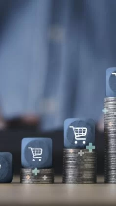 Carrinho de compras empilhado no topo do empilhamento de moedas crescentes para o conceito de crescimento de negócios de venda online.