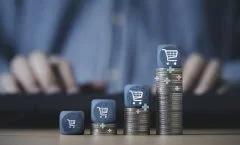 Carrinho de compras empilhado no topo do empilhamento de moedas crescentes para o conceito de crescimento de negócios de venda online.