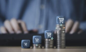 Carrinho de compras empilhado no topo do empilhamento de moedas crescentes para o conceito de crescimento de negócios de venda online.