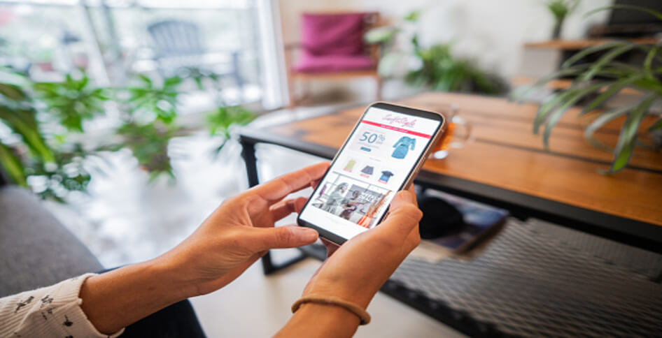 Consumidor finaliza compra pelo celular em loja virtual durante a Black Friday, com página de produto e carrinho na tela.